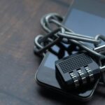 Close-up of a smartphone wrapped in a chain with a padlock, symbolizing strong security.
