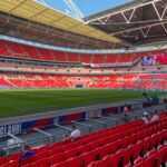 A vibrant view of Wembley Stadium with bright red seats and a well-maintained green field.